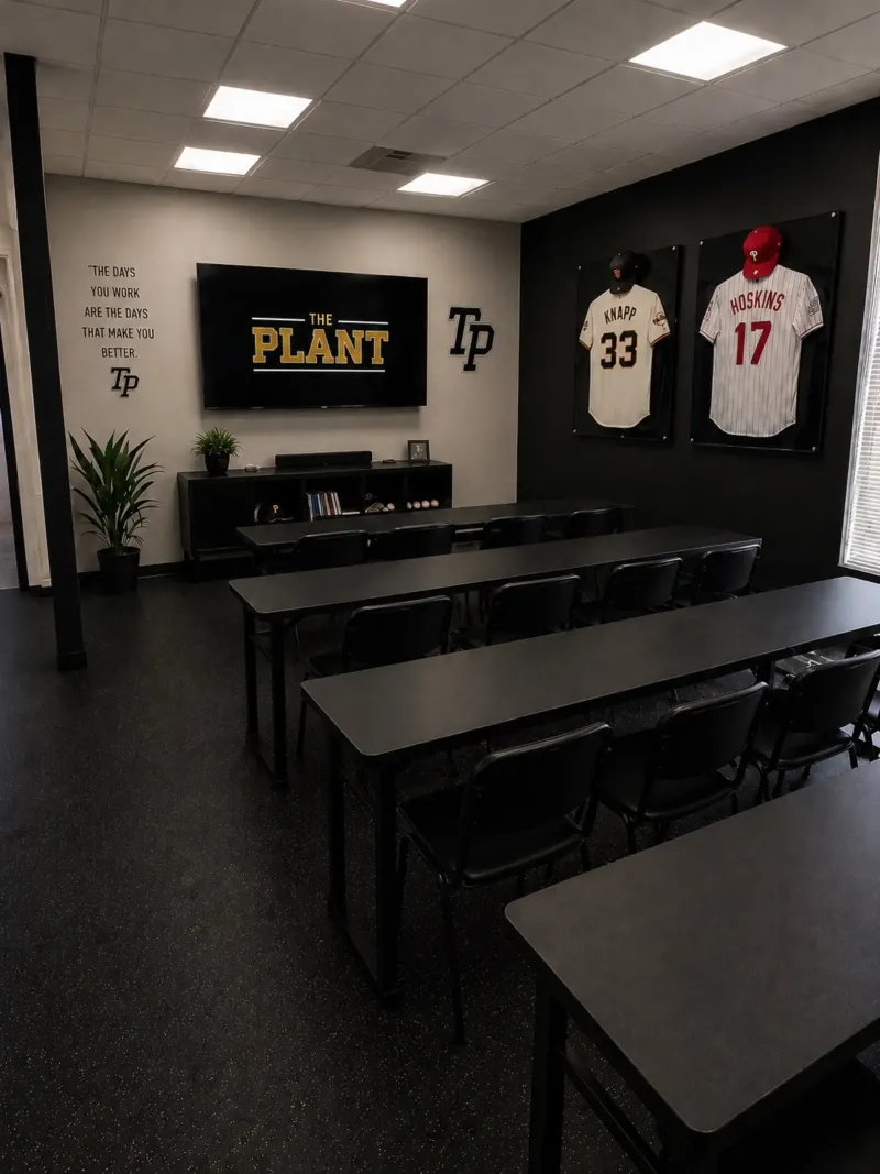 The classroom, with tables and chairs facing a screen and jerseys on the wall.
