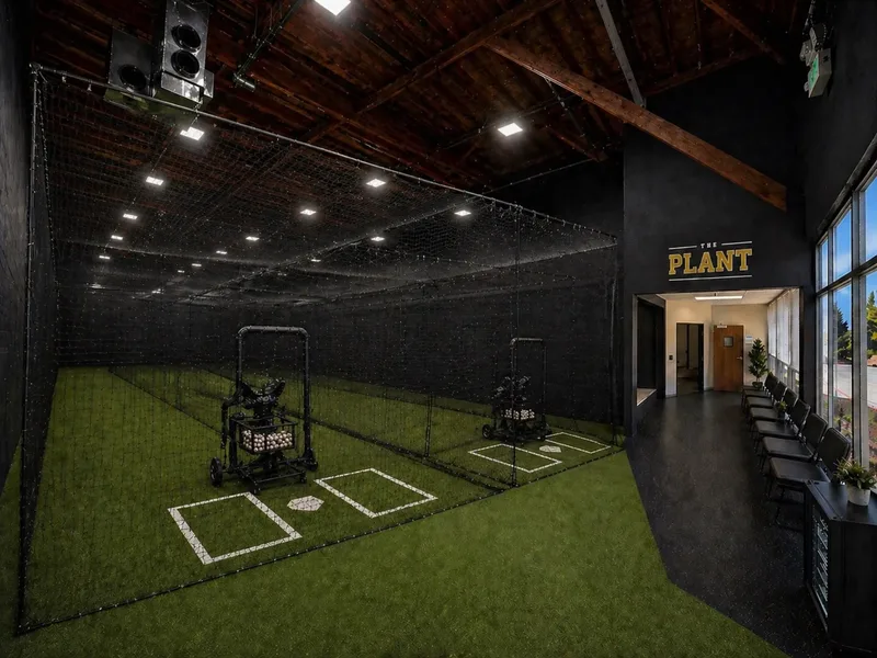 The main turf floor at Baseball Power Plant, set up as one open field with netting overhead.